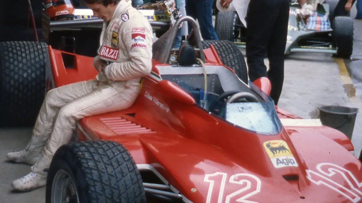 Gilles Villeneuve i tävlingsoverall sittande på sin röda Ferrari nummer 12 i depån.