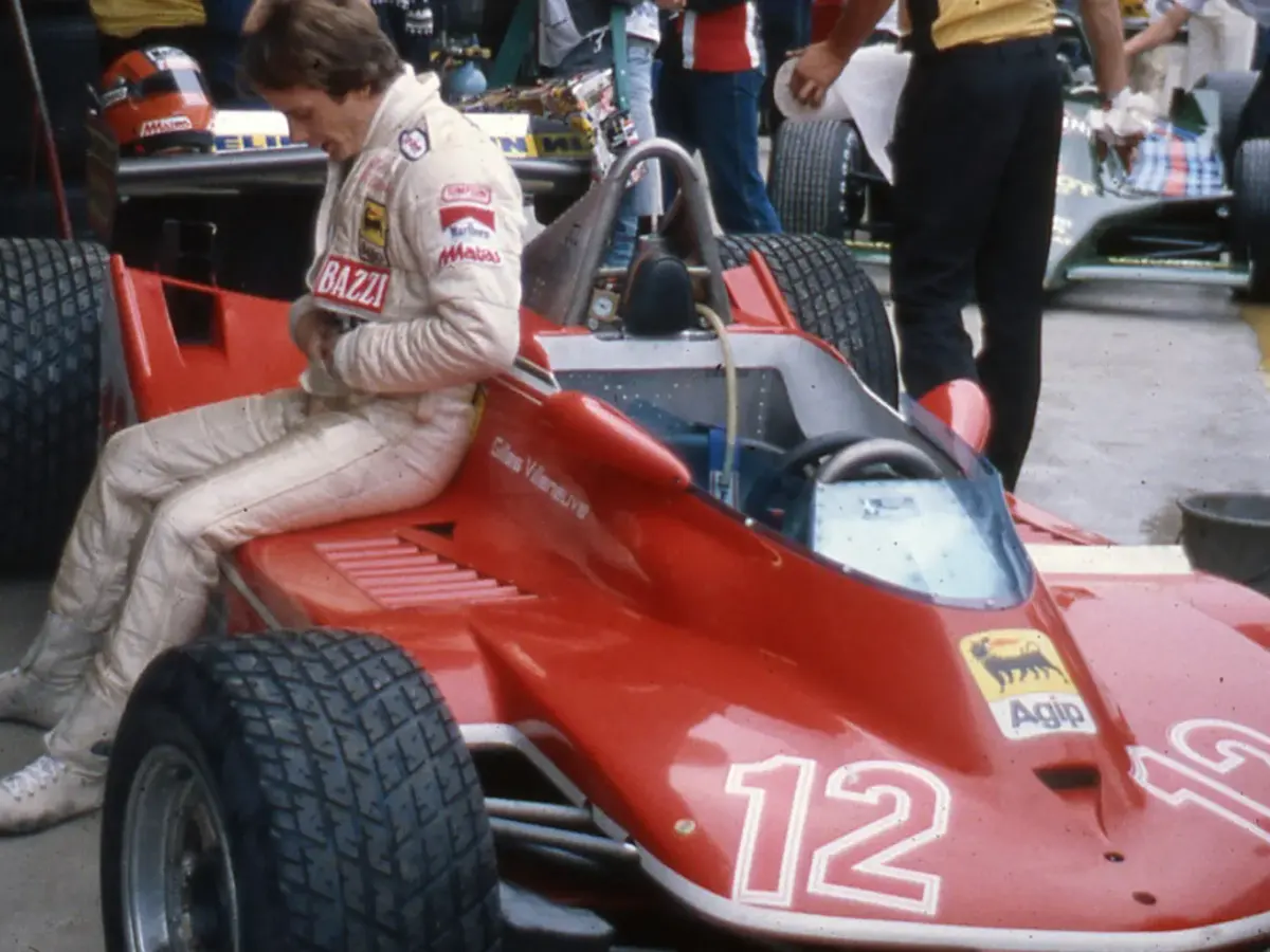 Gilles Villeneuve i tävlingsoverall sittande på sin röda Ferrari nummer 12 i depån.
