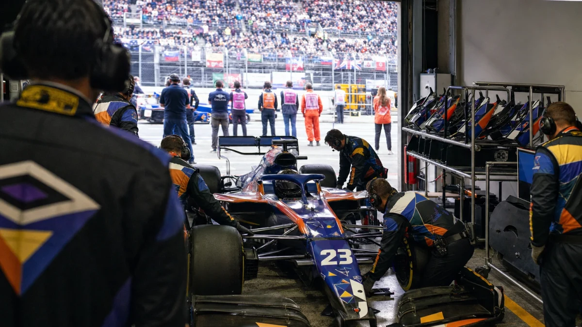 Formel 1-bil delvis isärtagen i ett garage med chassi, motor och vingar synliga.