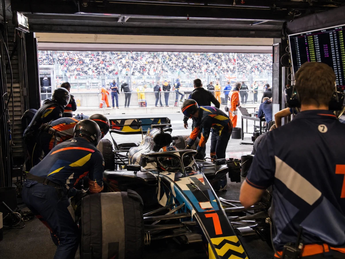 Formel 1-bilar i depågaraget under en kvalomgång med tidtavlan i bakgrunden.