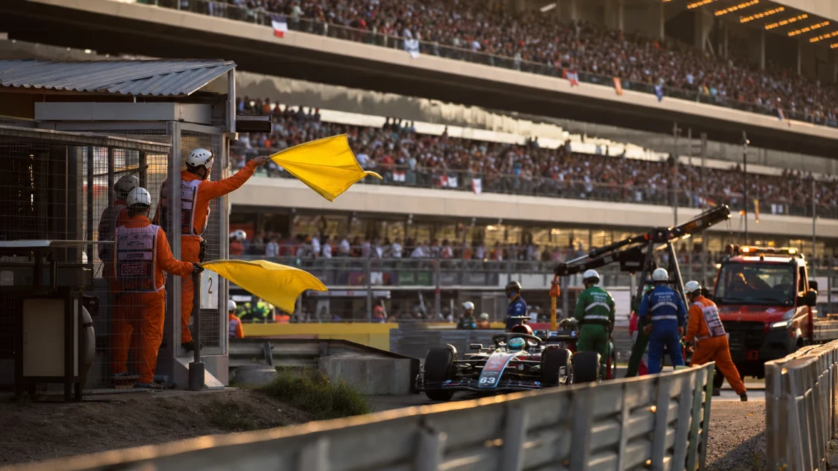 Formel 1-bil på Red Bull Ring i eftermiddagsljus med gula flaggljus tända vid en kurva i bakgrunden.
