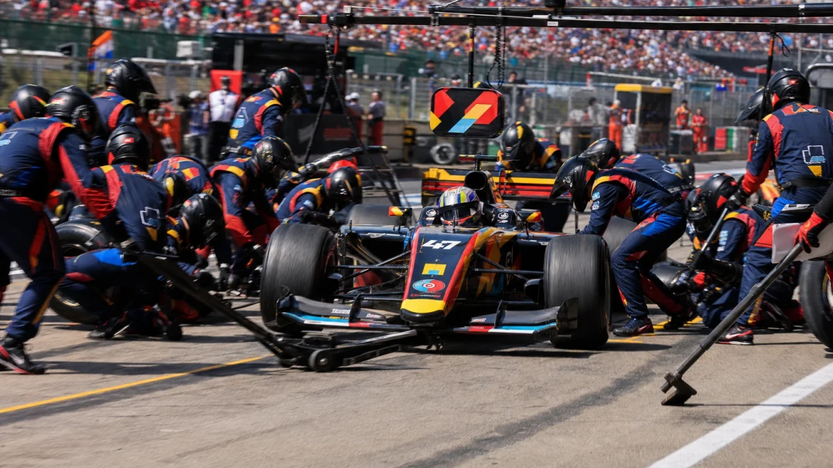 Formel 1-bil i depån med mekaniker runt om som byter alla fyra däcken samtidigt.