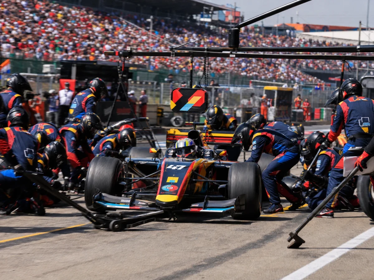 Formel 1-bil i depån med mekaniker runt om som byter alla fyra däcken samtidigt.